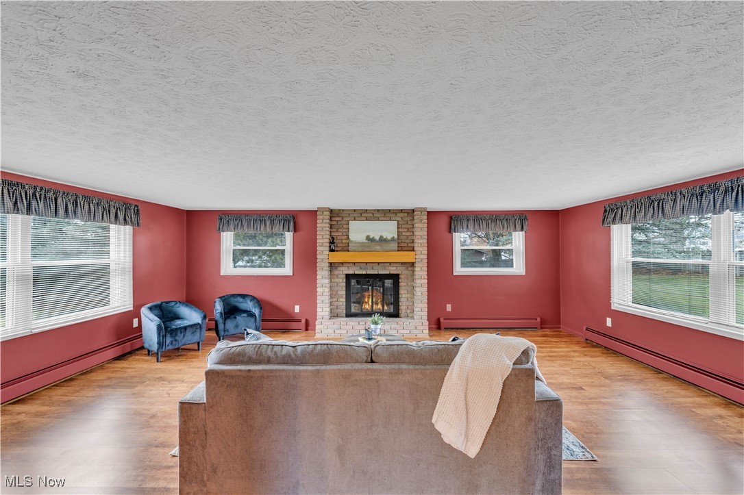 506 Logan Road Mansfield, OH 44907 - Photo 7 of 46 Living room with healthy amount of natural light, a baseboard radiator, a fireplace, and a textured ceiling