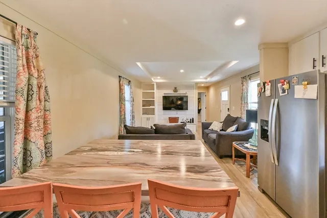 a kitchen with stainless steel appliances a sink a stove a refrigerator cabinets and a dining table with wooden floor