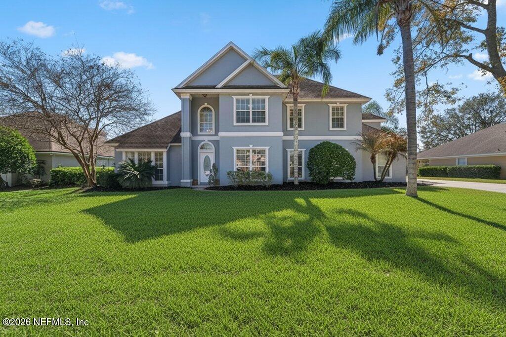 a front view of a house with a yard and green space