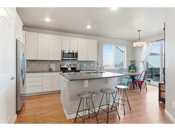 a kitchen with stainless steel appliances granite countertop a table chairs sink refrigerator and cabinets