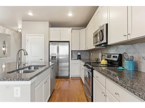 a kitchen with kitchen island granite countertop a sink stainless steel appliances and cabinets