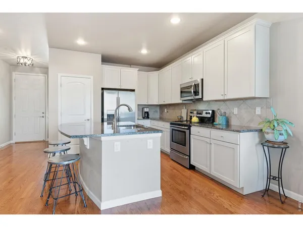 a kitchen with kitchen island granite countertop a sink cabinets and stainless steel appliances