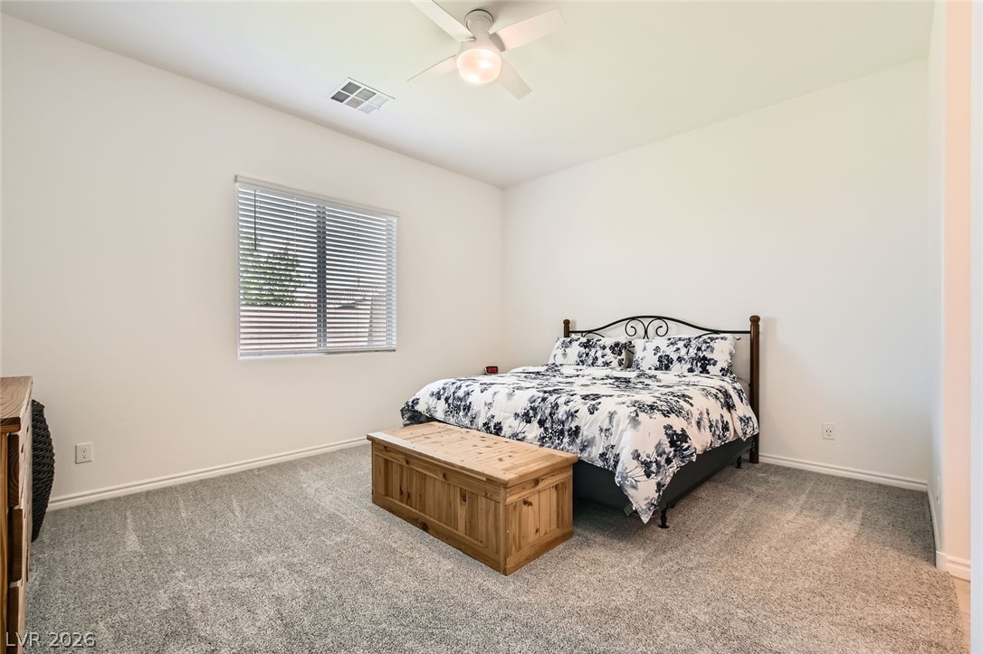 498 Pebble Run Avenue Henderson, NV 89011 - Photo 10 of 47 A well-lit bedroom features plush carpeting and a window for natural light.