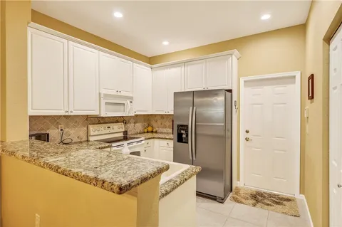 a kitchen with stainless steel appliances granite countertop a refrigerator a stove and a sink