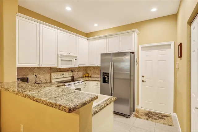 a kitchen with stainless steel appliances granite countertop a refrigerator a stove and a sink