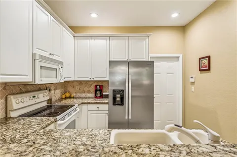 a kitchen with stainless steel appliances granite countertop a refrigerator a sink and a stove
