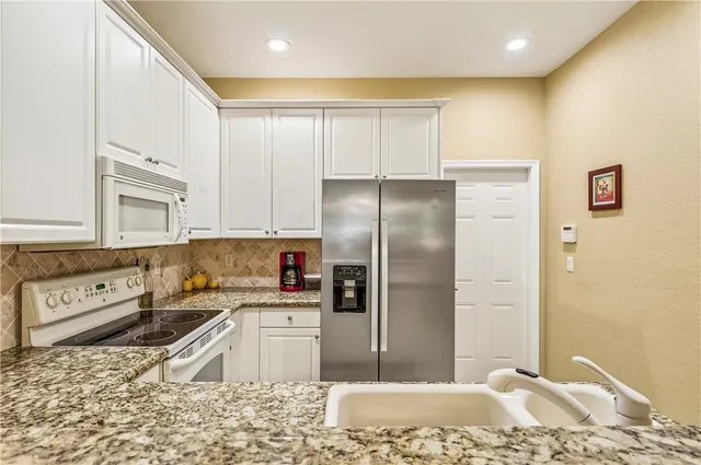 a kitchen with stainless steel appliances granite countertop a refrigerator a sink and a stove