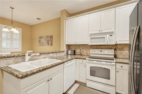 a kitchen with granite countertop white cabinets and white appliances