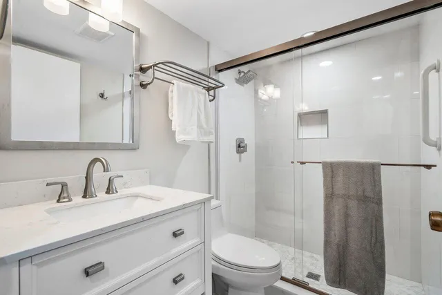 a bathroom with a sink a mirror a toilet and shower