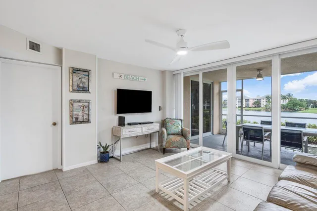 a living room with furniture a flat screen tv and a floor to ceiling window