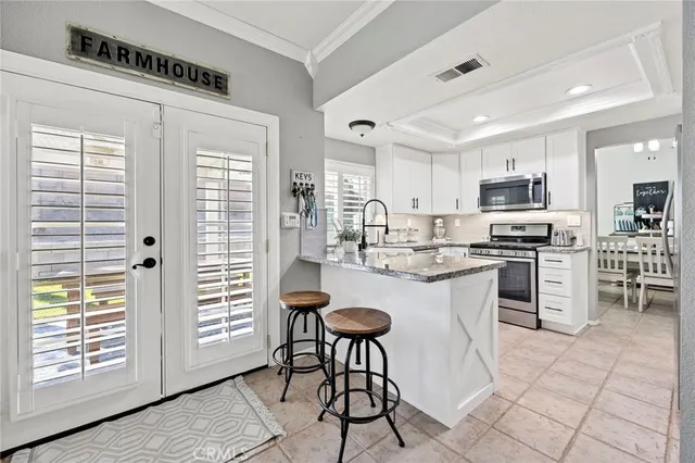 a kitchen with stainless steel appliances granite countertop a stove top oven a sink a dining table and chairs