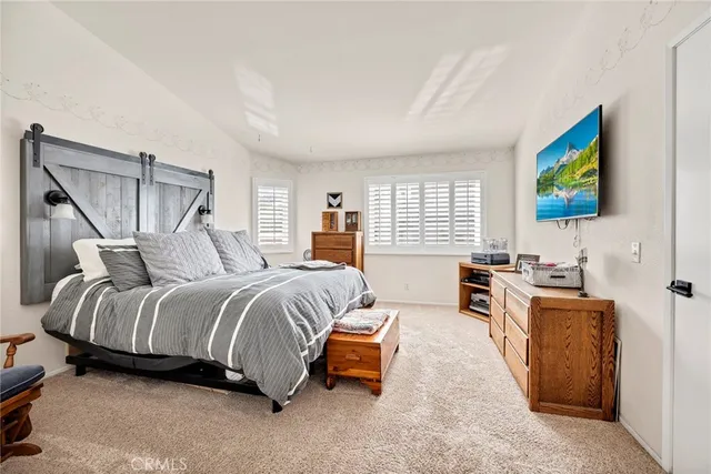 a spacious bedroom with a bed and a flat screen tv