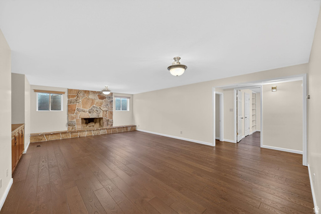 3120 North Apache Way Provo, UT 84604 - Photo 36 of 58 Spacious room featuring wood-finish flooring, a stone-clad fireplace with a stone hearth, and two windows with blinds