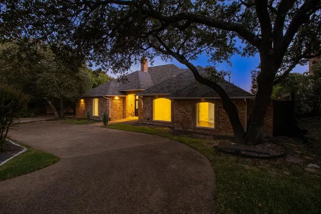 a front view of a house with a garden and trees