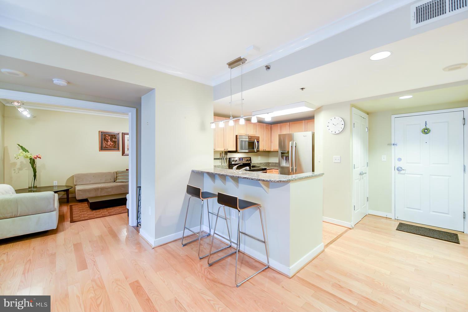 777 7th Street Northwest, Unit 1113 Washington, DC 20001 - Photo 7 of 30 a open kitchen with stainless steel appliances kitchen island granite countertop a refrigerator and cabinets