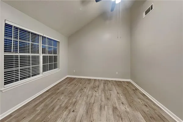 a view of an empty room with wooden floor and a window