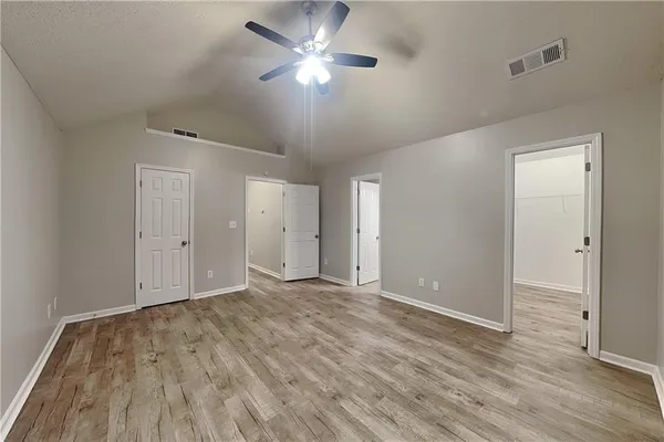 an empty room with wooden floor ceiling fan and windows
