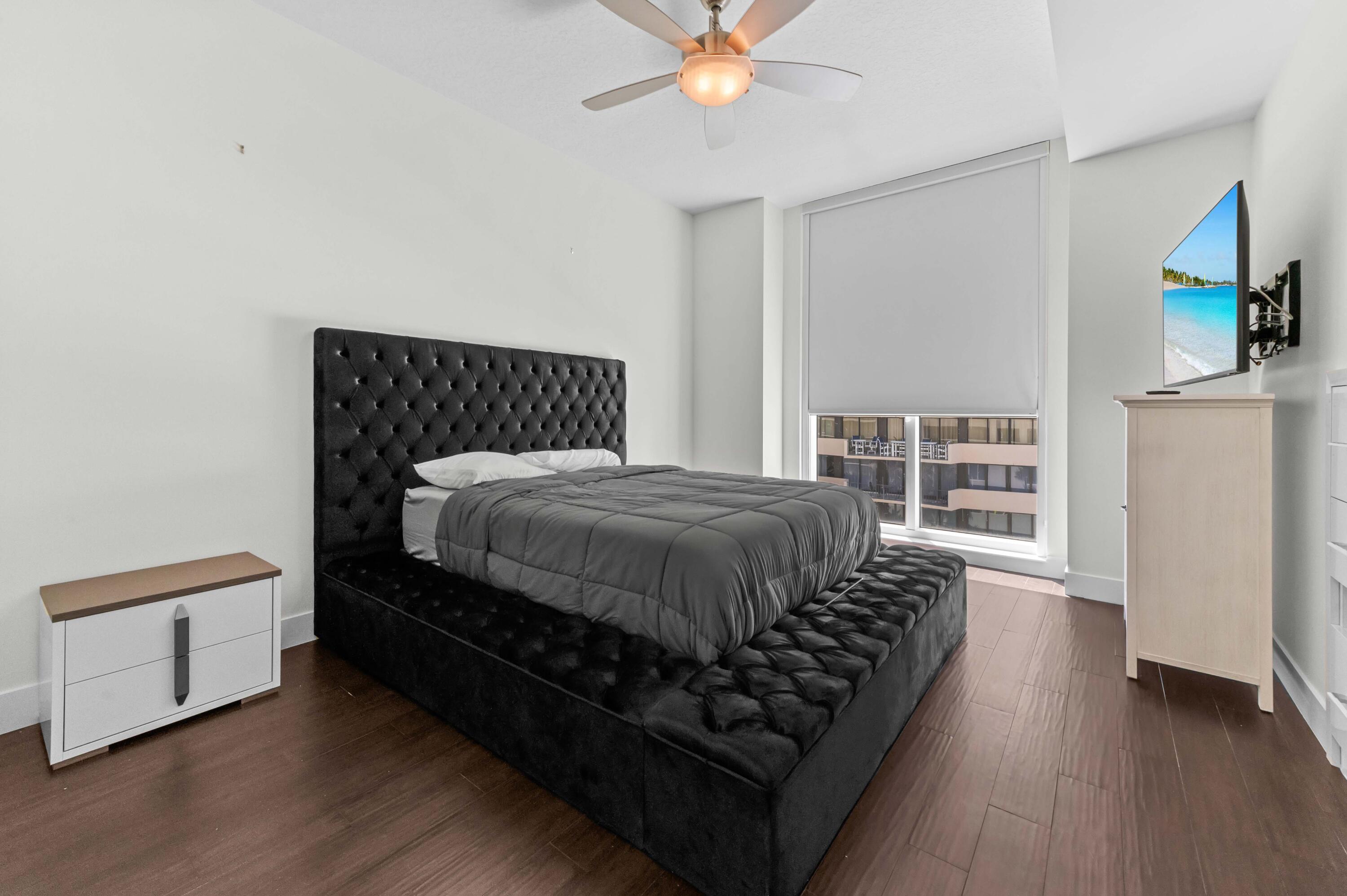 4600 North Ocean Drive, Unit 605 Riviera Beach, FL 33404 - Photo 28 of 65 a bed sitting in a bedroom next to a window with a chandelier