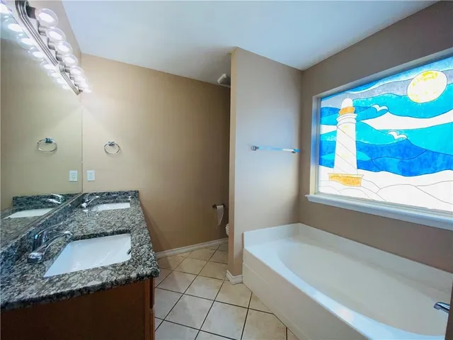 a bathroom with a granite countertop sink and a bathtub