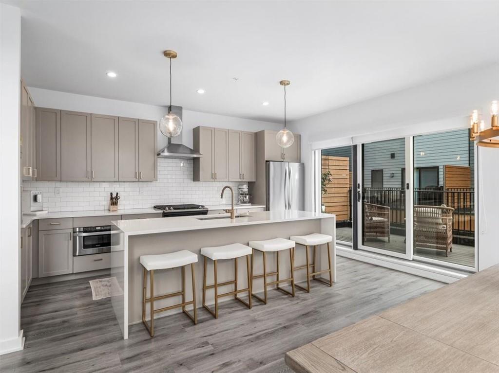 5557 Berlin Way Pittsburgh, PA 15201 - Photo 11 of 34 a kitchen with stainless steel appliances granite countertop a stove a sink dishwasher a refrigerator and a dining table with wooden floor