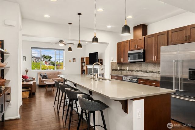 a kitchen with stainless steel appliances granite countertop a stove a refrigerator a kitchen island a dining table and chairs