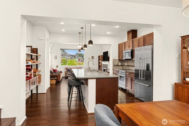 a kitchen with stainless steel appliances kitchen island granite countertop a refrigerator a stove and a wooden floors
