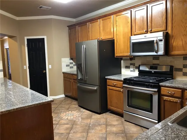 a kitchen with stainless steel appliances granite countertop a refrigerator stove and microwave