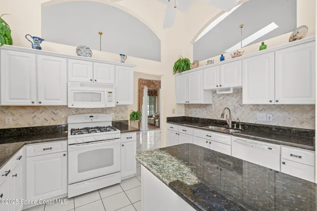 a kitchen with granite countertop white cabinets and white appliances
