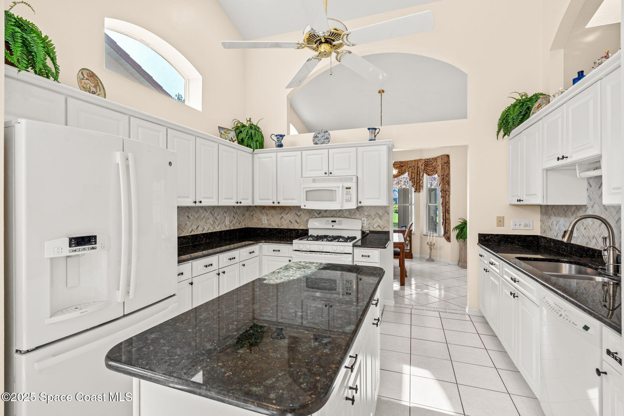 7702 Candlewick Drive Melbourne, FL 32940 - Photo 16 of 37 a kitchen with stainless steel appliances granite countertop a stove a sink a refrigerator and white cabinets