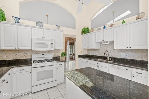 a kitchen with granite countertop white cabinets and white appliances