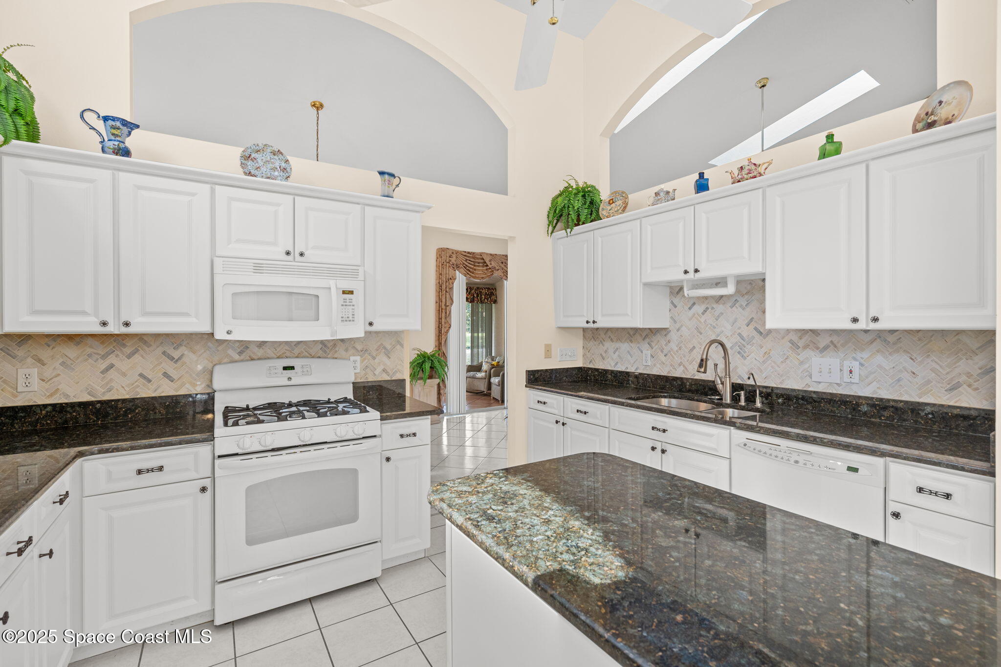 7702 Candlewick Drive Melbourne, FL 32940 - Photo 18 of 37 a kitchen with granite countertop white cabinets and white appliances