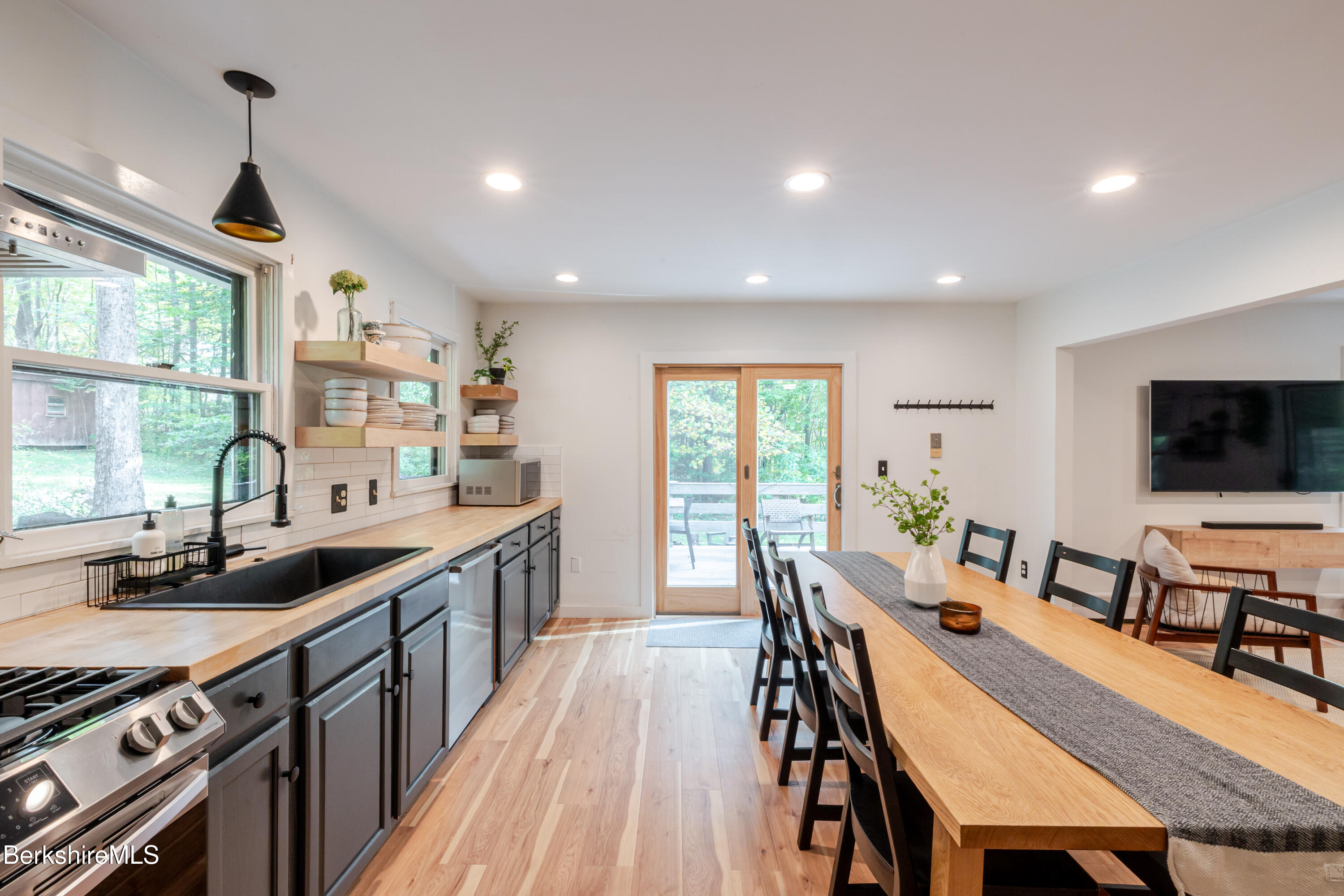 176 Division Street Great Barrington, MA 01230 - Photo 8 of 40 a kitchen with stainless steel appliances granite countertop a stove a sink dishwasher a dining table and chairs with wooden floor