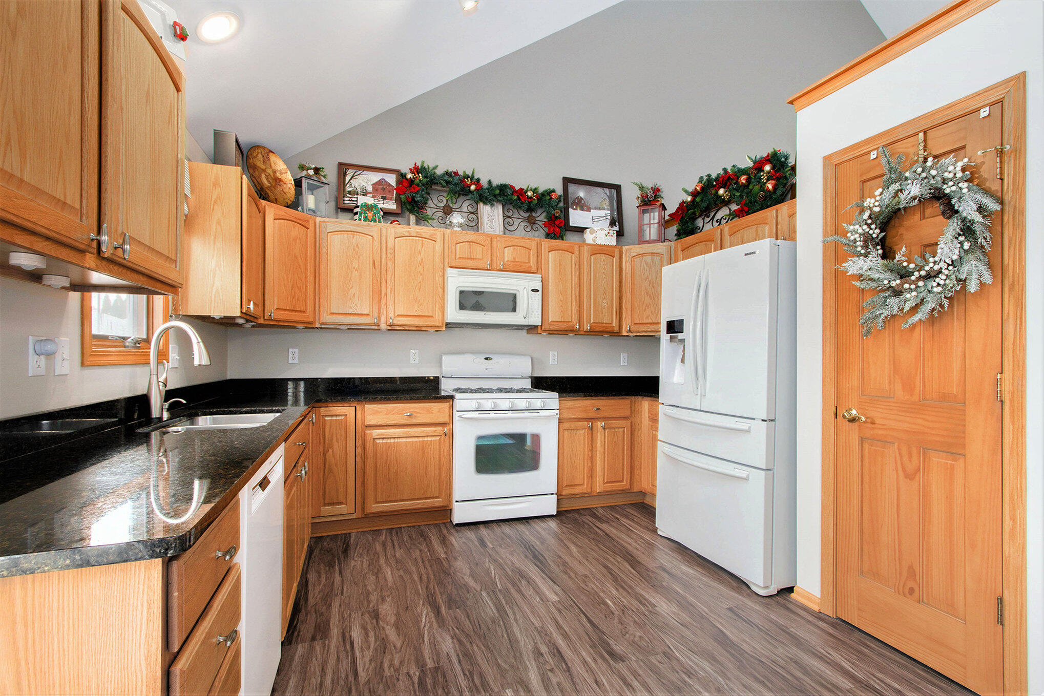 10399 Pike Street Crown Point, IN 46307 - Photo 6 of 25 a kitchen with granite countertop a refrigerator a sink and wooden floors