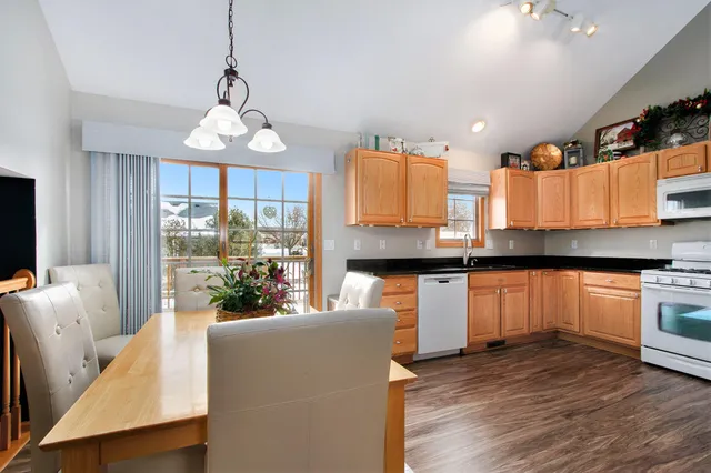 a kitchen with stainless steel appliances granite countertop a stove top oven a sink dishwasher a dining table and chairs with wooden floor