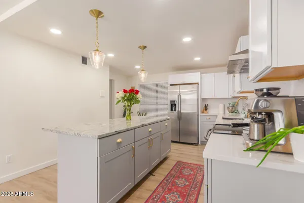 a kitchen that has a lot of cabinets and stainless steel appliances