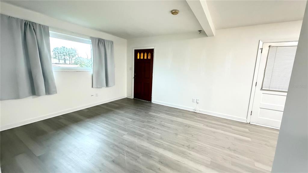 6310 Lake Underhill Road, Unit A Orlando, FL 32807 - Photo 3 of 12 a view of an empty room with wooden floor and a window