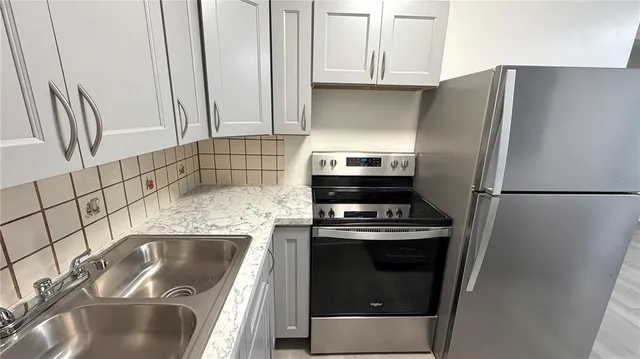 a kitchen with granite countertop a sink stove and refrigerator