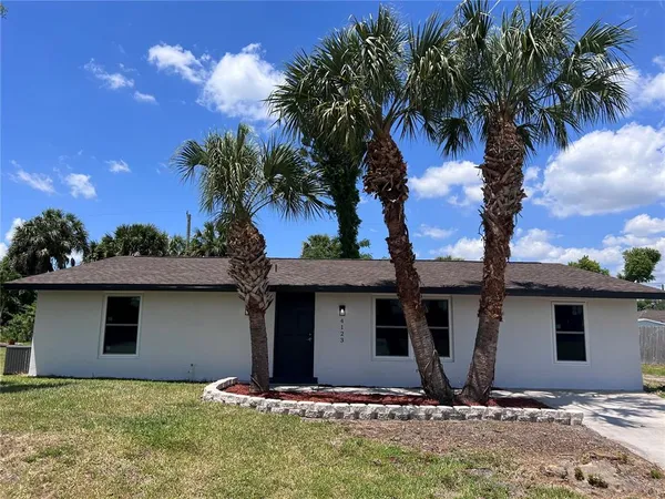 a view of a house with a yard and palm trees