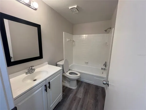 a bathroom with a bathtub shower sink vanity and toilet
