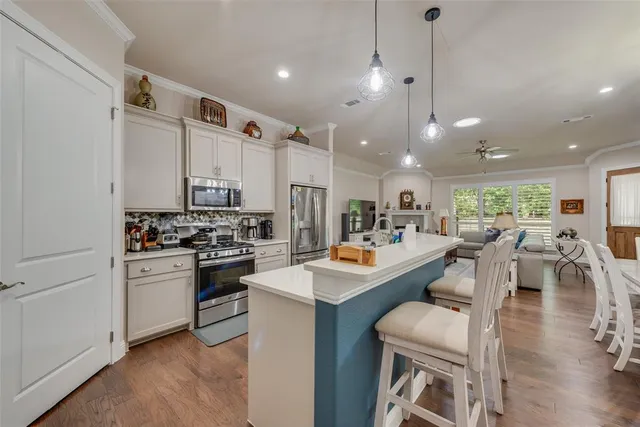 a kitchen with a sink stove and white cabinets with wooden floor