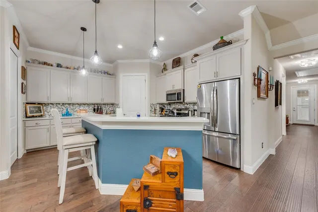 a kitchen with stainless steel appliances granite countertop a refrigerator a sink dishwasher a stove and a microwave oven with wooden floor