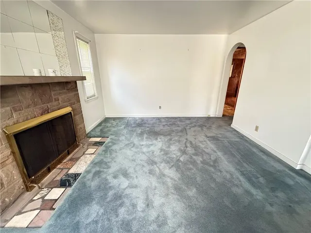 a view of an empty room with wooden floor and a fireplace