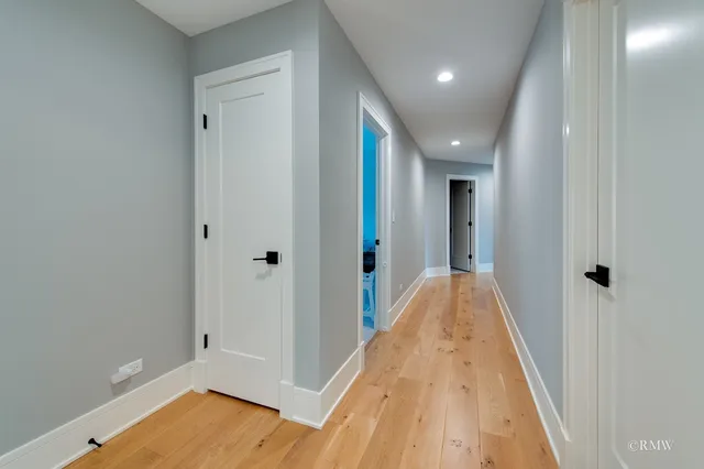 a view of a hallway with wooden floor and a bathroom