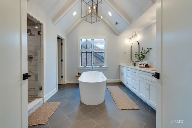 a spacious bathroom with a double vanity sink a large mirror a bathtub and shower