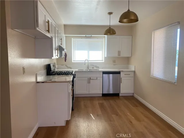 a kitchen with a sink a window stainless steel appliances and cabinets