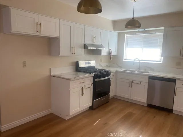 a kitchen with granite countertop white cabinets white appliances a sink and a window
