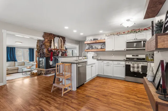 a kitchen with stainless steel appliances a microwave a stove a sink dishwasher and cabinets with wooden floor