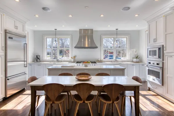 a kitchen with granite countertop a table chairs stove and refrigerator