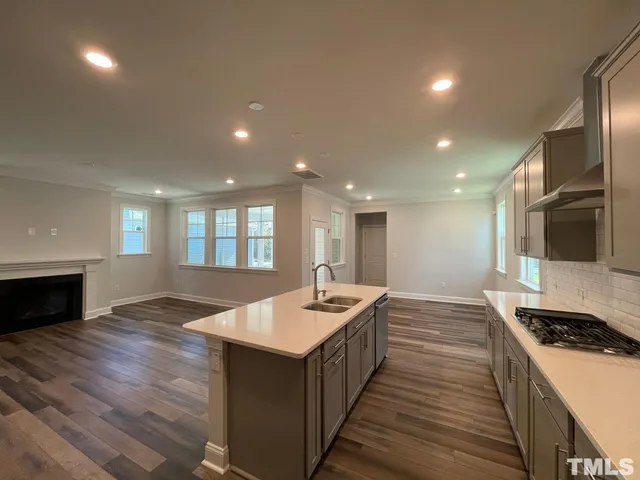 a open kitchen with kitchen island a sink wooden floor and a stove