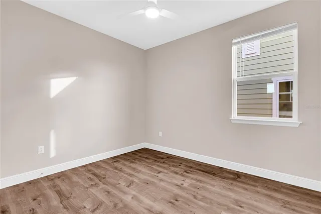 a view of empty room with wooden floor and fan